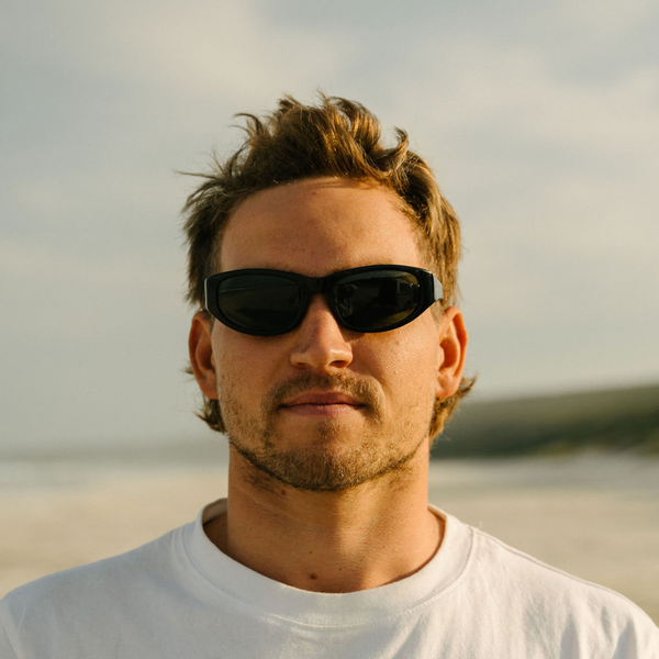 Man wearing sunglasses with a blurred beach background