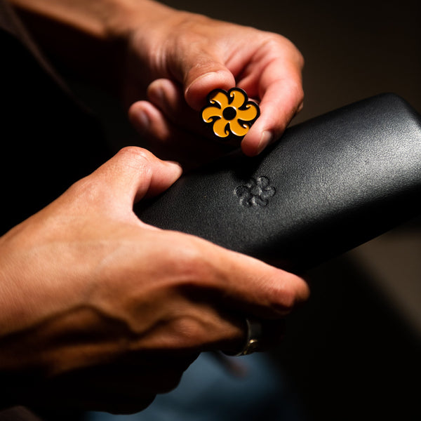 Artist Kentaro Yoshida holding sunglasses case and enamel flower pin