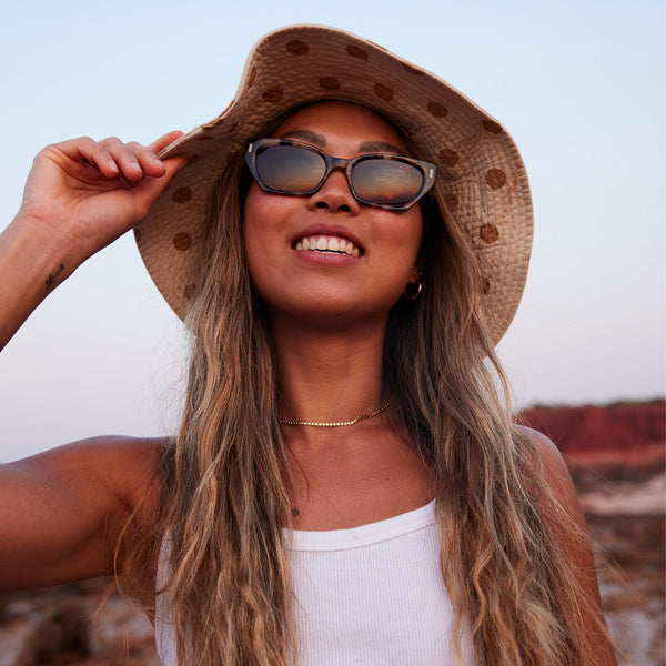 Girl wearing hat and sunglasses looking up and smiling
