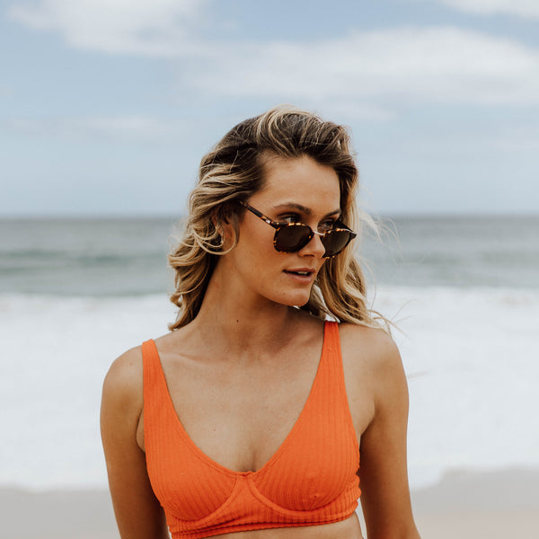 Girl in orange bikini wearing round tort sunglasses