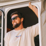 Man standing under a door wearing a shirt and dark sunglasses