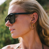 Woman wearing aviator sunglasses with a blurred natural background