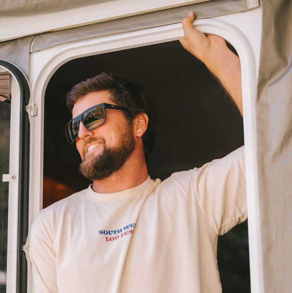 Man standing under a door wearing a shirt and dark sunglasses