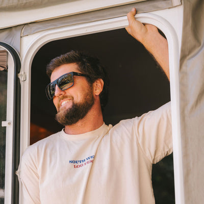 Man standing under a door wearing a shirt and dark sunglasses
