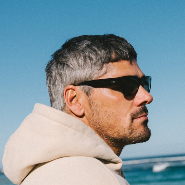 Man wearing sunglasses with a clear blue sky and water in the background