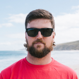 Man wearing red shirt and black square sunglasses. 