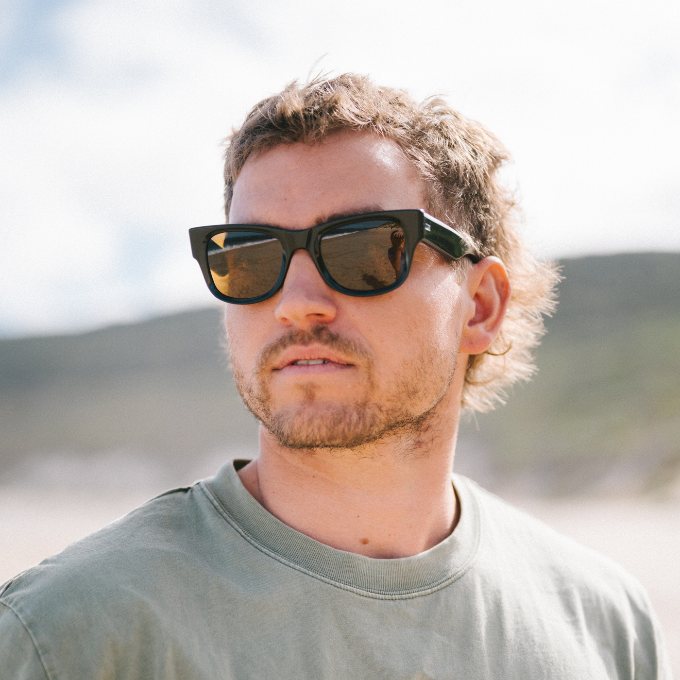 Man wearing wayfarer sunglasses with a blurred natural background