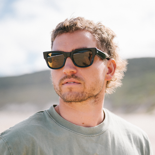 Man wearing wayfarer sunglasses with a blurred natural background