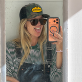 Blonde woman taking seflie in a trucker cap and aviator sunglasses
