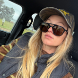 Woman in car wearing camouflage cap and brown lens aviator sunglasses 