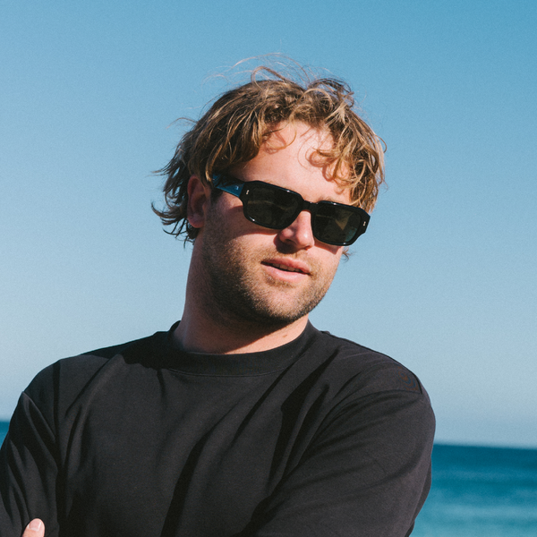 Man wearing black sunglasses with a clear blue sky and ocean background