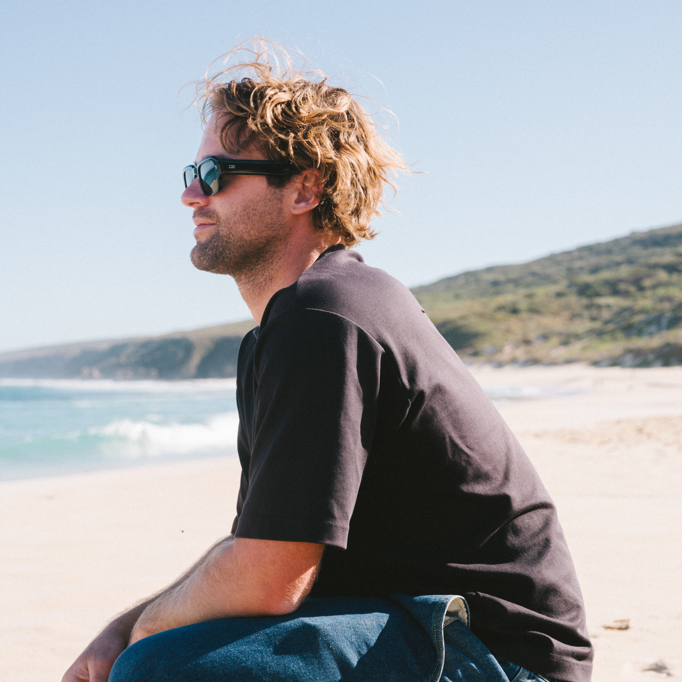 Man wearing black sunglasses with a clear blue sky and ocean background