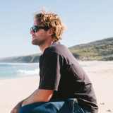 Man wearing black sunglasses with a clear blue sky and ocean background