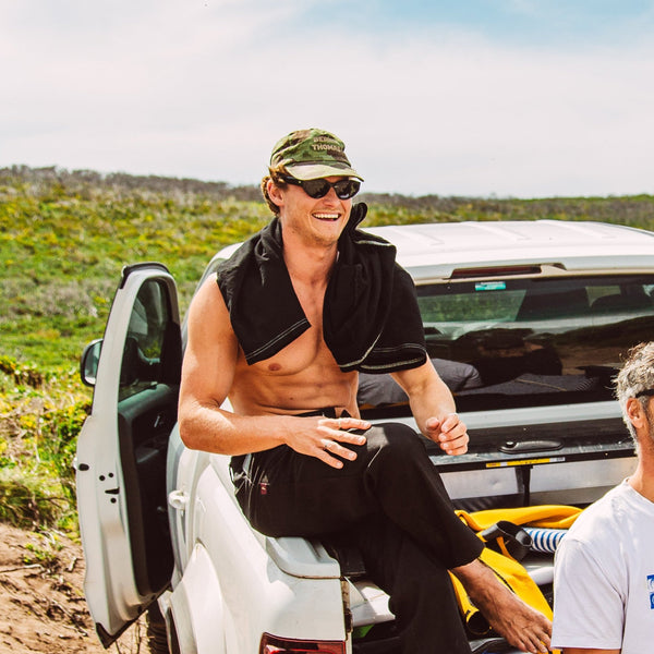 Man sitting in hat and black sunglasses smiling