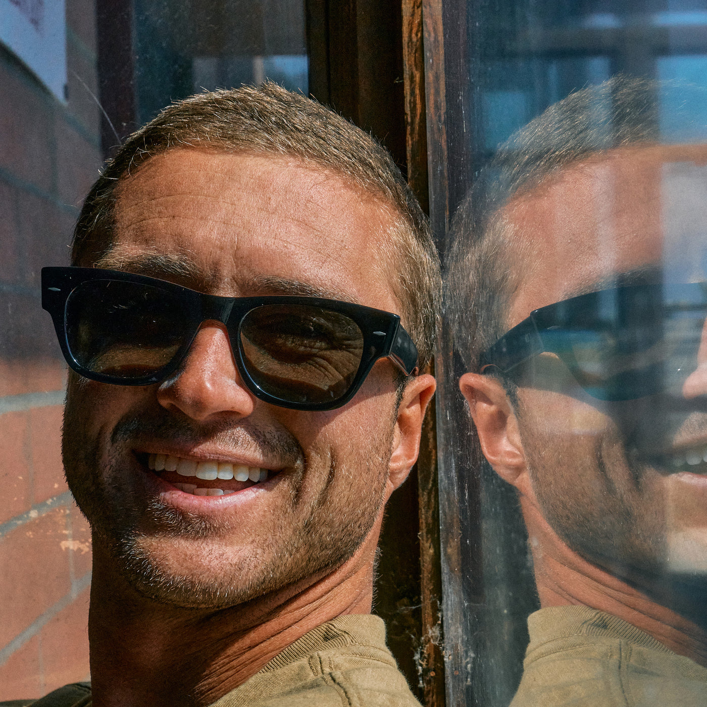 Man sitting next to a window wearing black sunglasses
