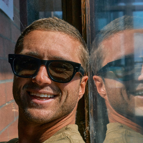 Man sitting next to a window wearing black sunglasses