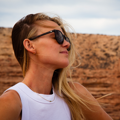 Imogen Caldwell in Kalbarri Western Australia wearing black OTIS Eyewear sunglasses looking the side and smiling