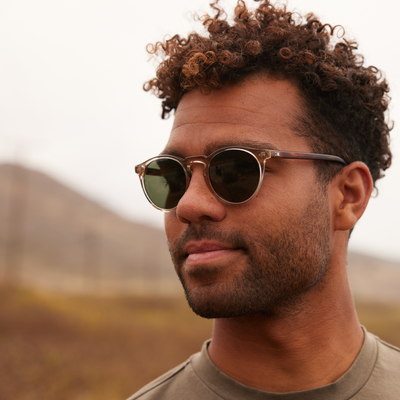 Man wearing round OTIS Eyewear sunglasses and a green shirt