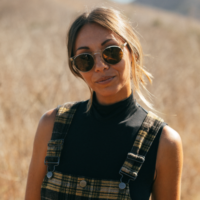 Female model wearing round sunglasses and overalls in the afternoon sun