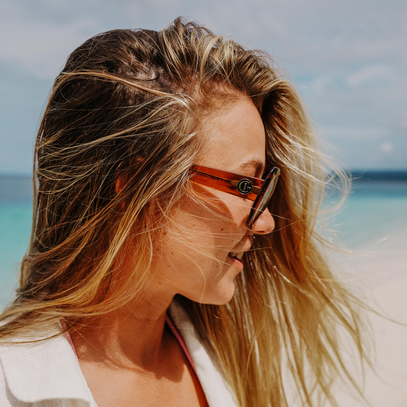 Imogen Caldwell at the beach wearing oversized sunglasses and looking to the side
