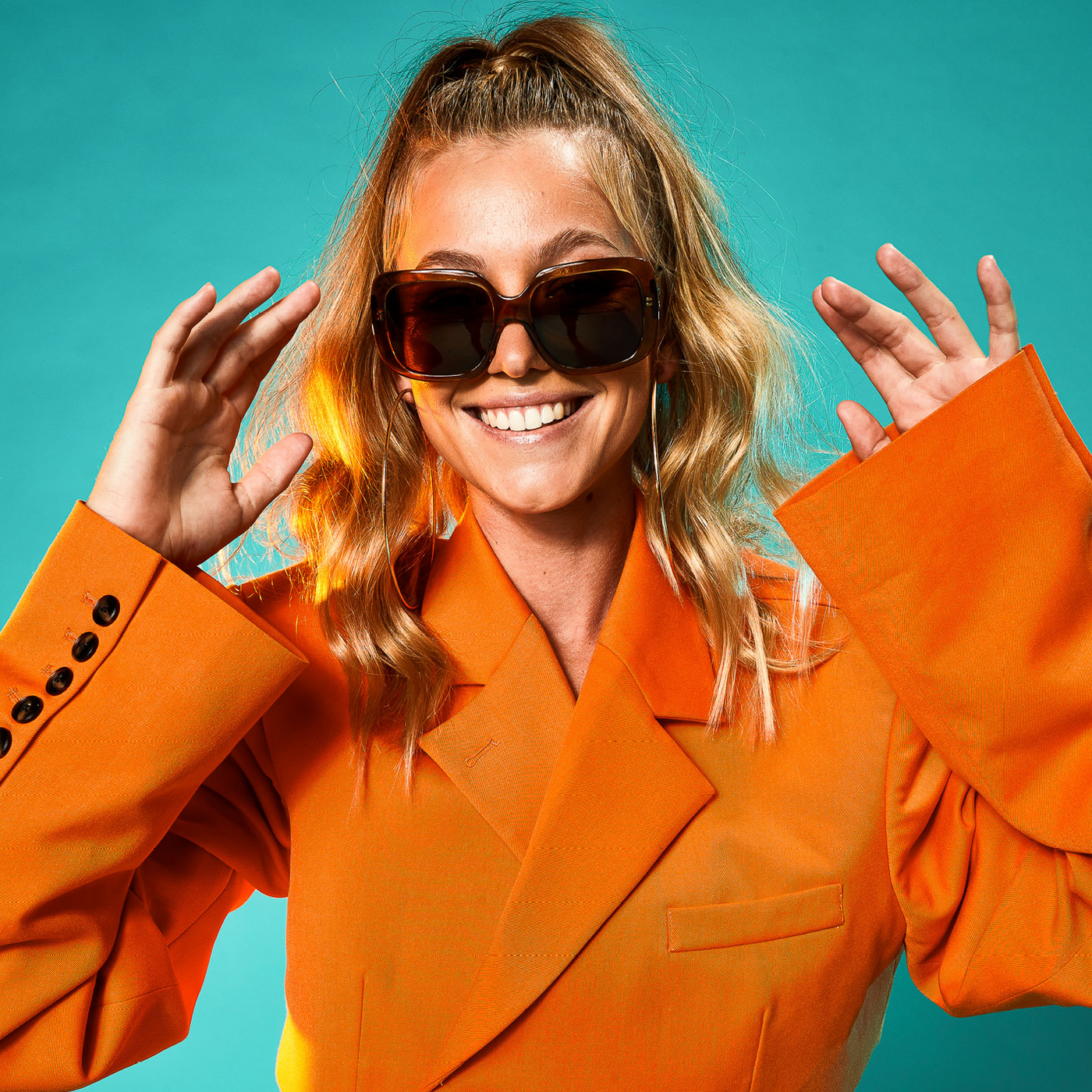 Imogen Caldwell wearing an orange jacket and oversized sunglasses