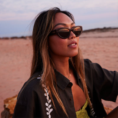 Woman wearing cat eye sunglasses at sunset on the beach