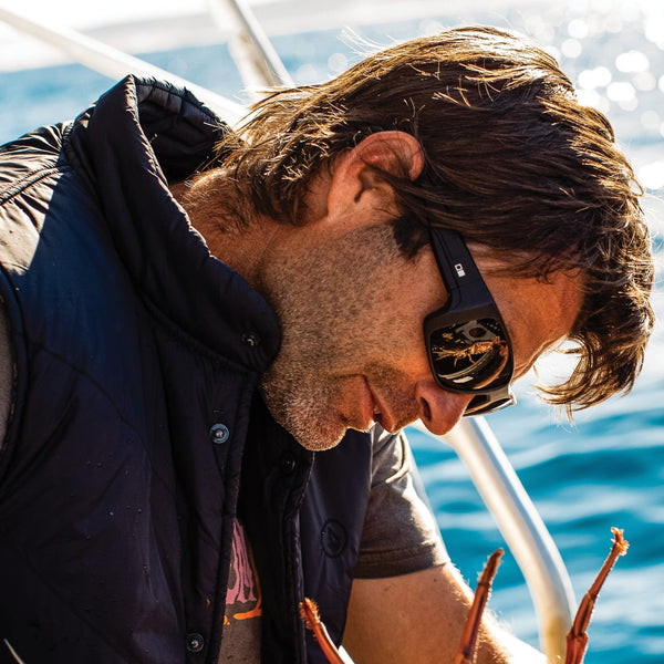 Fisherman measuring a crayfish and wearing OTIS Eyewear surfing sunglasses