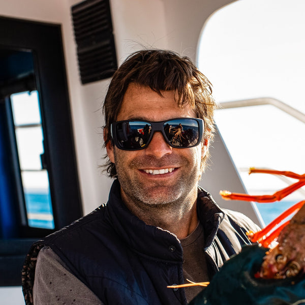 Fisherman holding a crayfish and smiling wearing OTIS Eyewear surfing sunglasses
