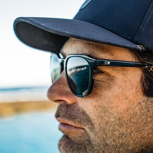 Man on a boat wearing a cap and surf ethical sunglasses