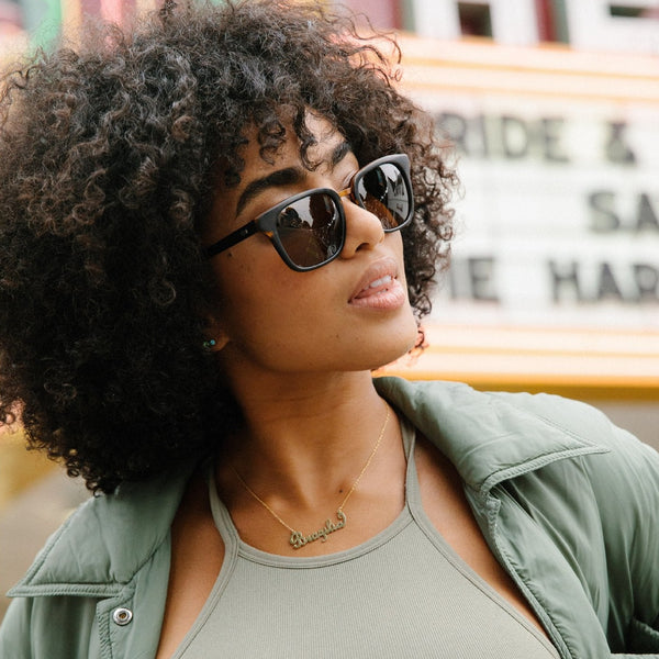 Model with curly hair wearing black and brown sunglasse