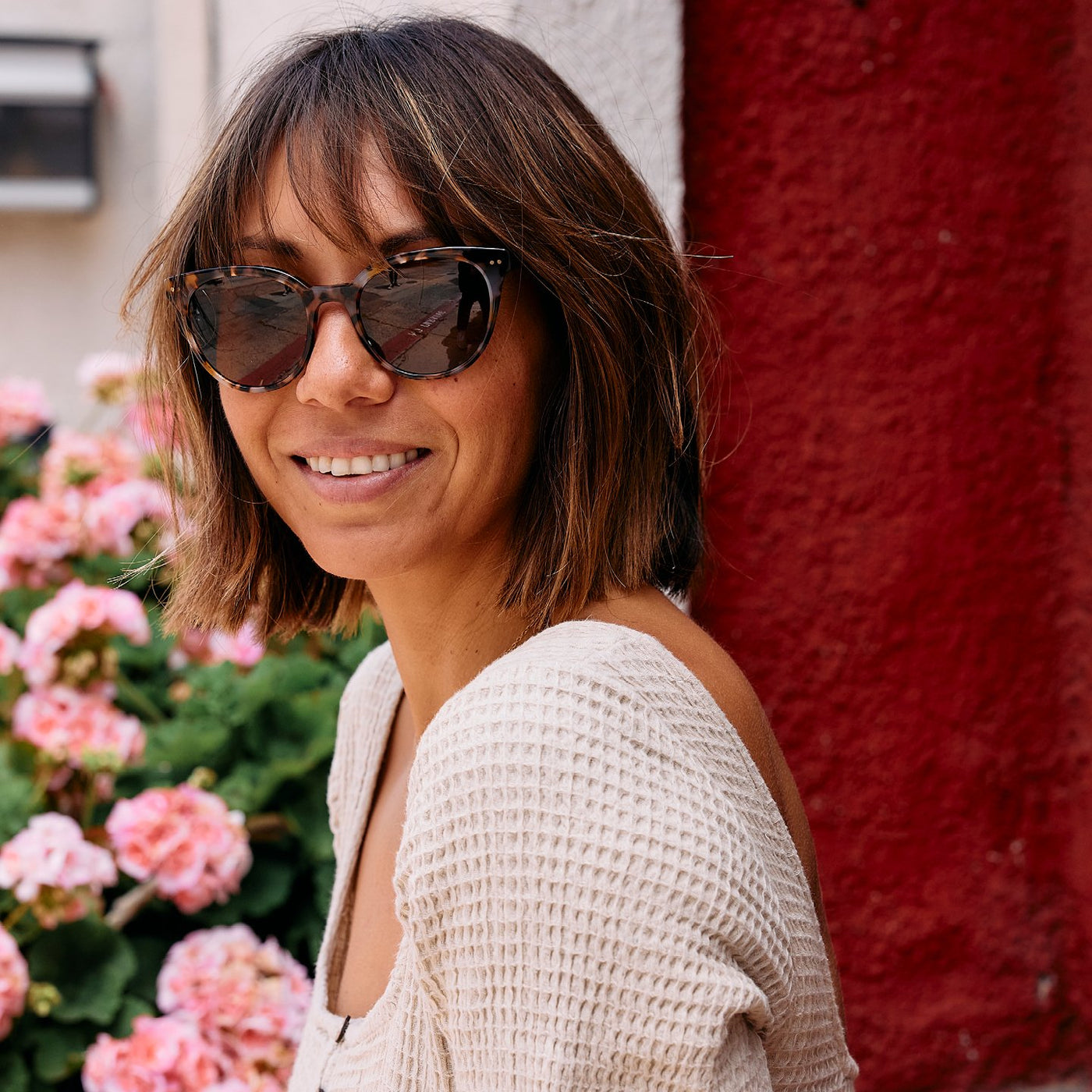 Woman sitting in front of flowers wearing sunglasses