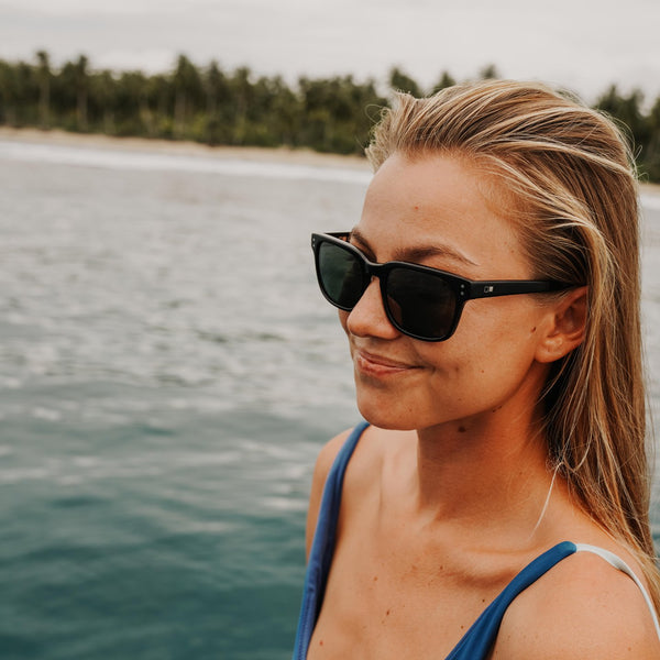 Imogen Caldwell wearing black sunglasses and smiling over the ocean