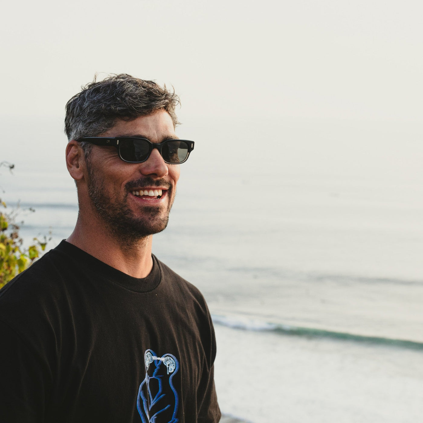 Jay Davies wearing surf sunglasses looking out at the ocean in Bali and smiling