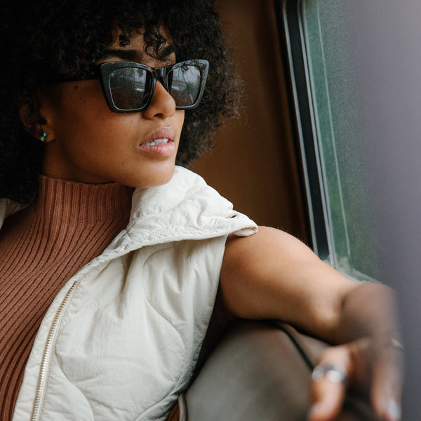 Female model wearing black sunglasses looking out of a window