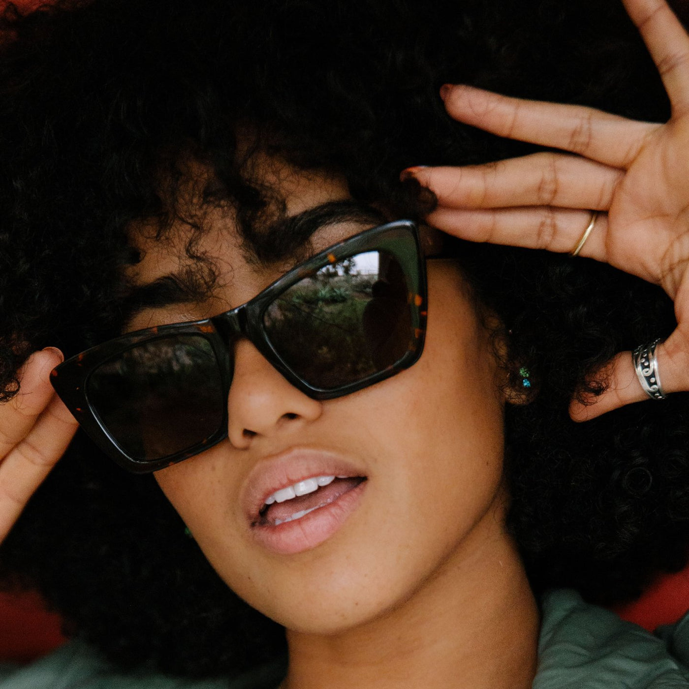 Female model wearing angular sunglasses and posing