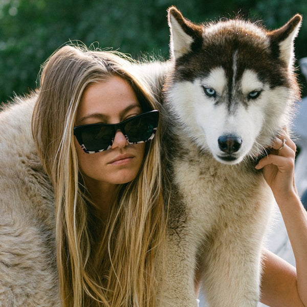 Imogen Caldwell wearing OTIS Eyewear sunglasses and holding a husky dog